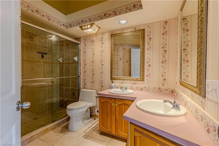 Primary full bath featuring vanity, shower stall, light tile patterned floors & recessed lighting.
