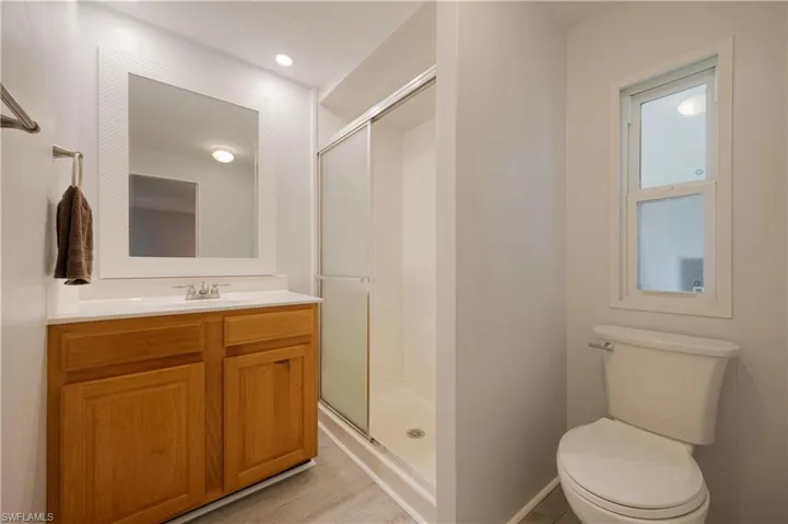 Bathroom featuring toilet, walk in shower, vanity, and hardwood / wood-style flooring