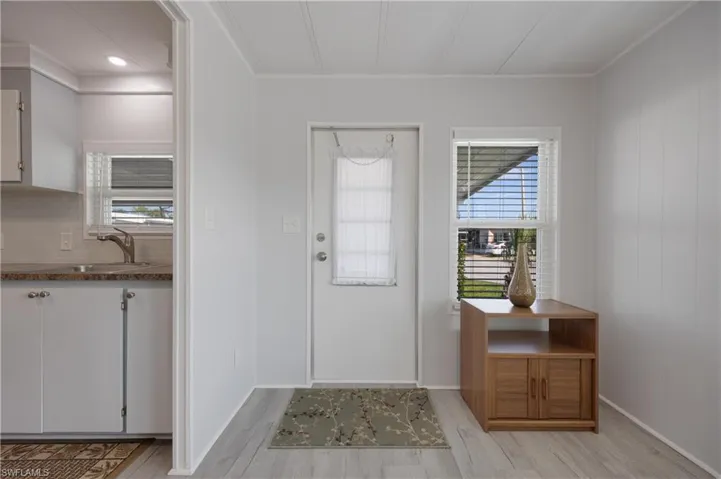 Doorway featuring wood walls, ornamental molding, sink, and light wood-type flooring