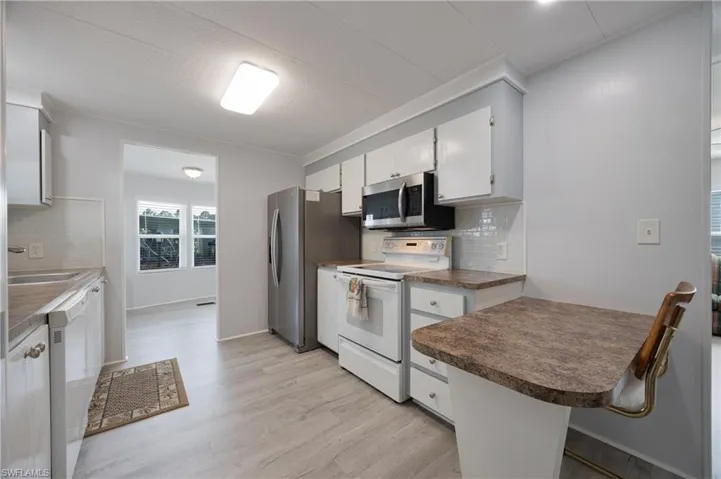 Kitchen featuring decorative backsplash, light hardwood / wood-style flooring, stainless steel appliances, sink, and white cabinets