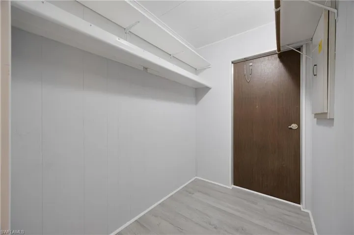 Walk in closet with light hardwood / wood-style flooring