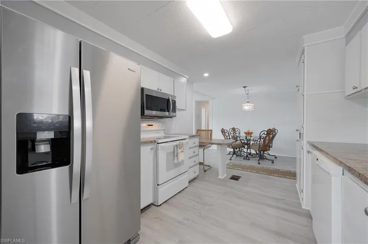 Kitchen featuring appliances with stainless steel finishes, light hardwood / wood-style flooring, pendant lighting, and white cabinetry