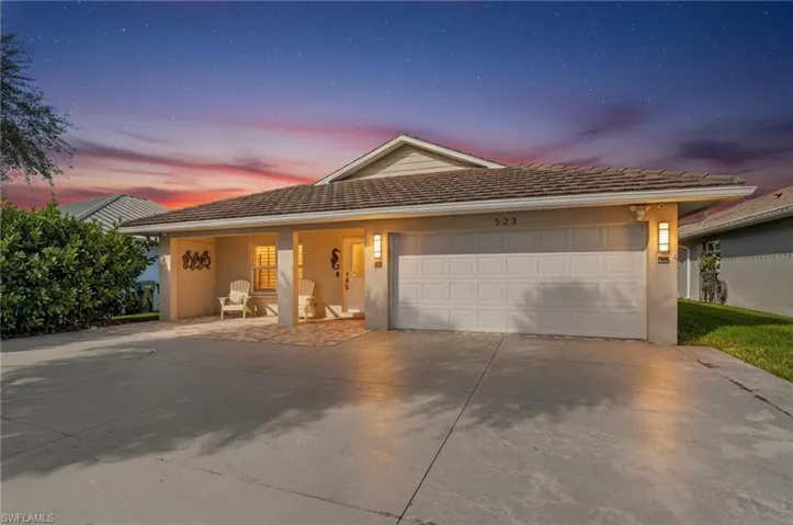 View of front of home featuring stucco siding, concrete driveway, covered porch, and an attached garage