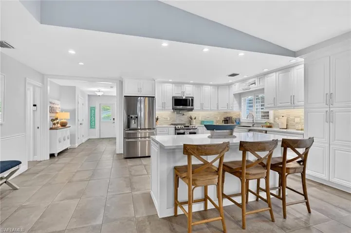 Kitchen featuring a breakfast bar area, white cabinets, recessed lighting, a kitchen island, and stainless steel appliances