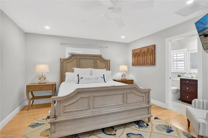 Bedroom featuring light wood-type flooring, ceiling fan, connected bathroom, multiple windows, and recessed lighting