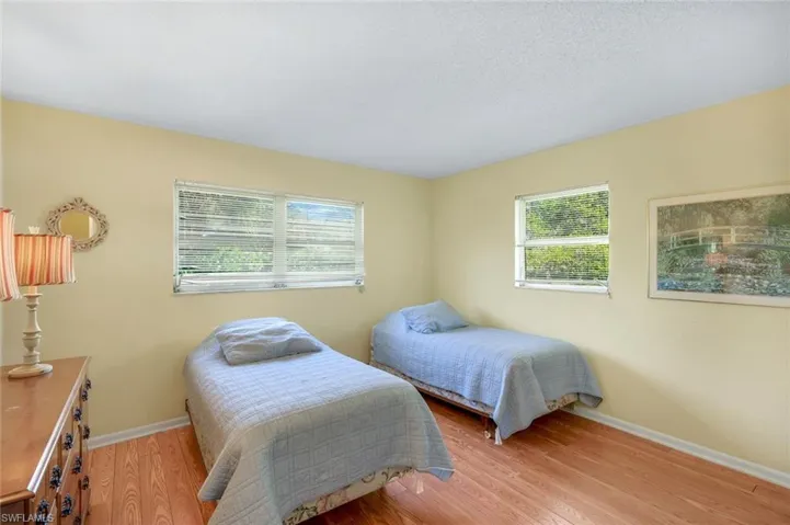 Bedroom with multiple windows affords a sunny and bright room with laminate wood flooring