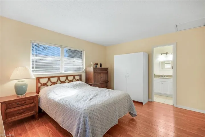 Bedroom featuring ensuite bath and easy care laminate wood flooring