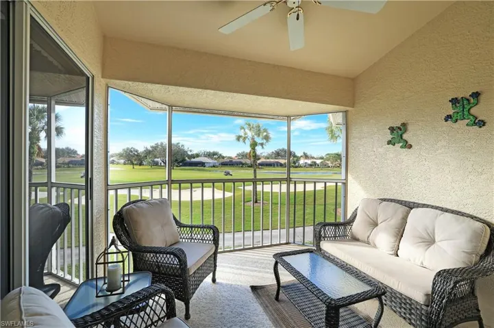 Sunroom featuring view of golf course, a ceiling fan, outdoor lounge area, and a water view