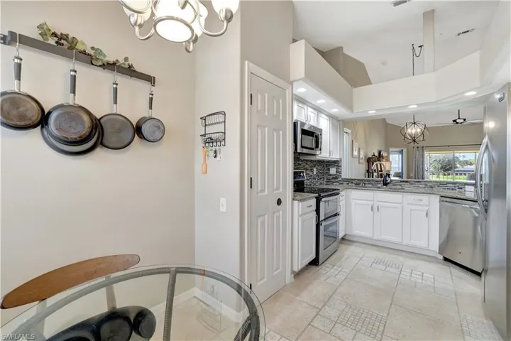 Kitchen featuring a chandelier, appliances with stainless steel finishes, recessed lighting, light stone countertops, and white cabinetry