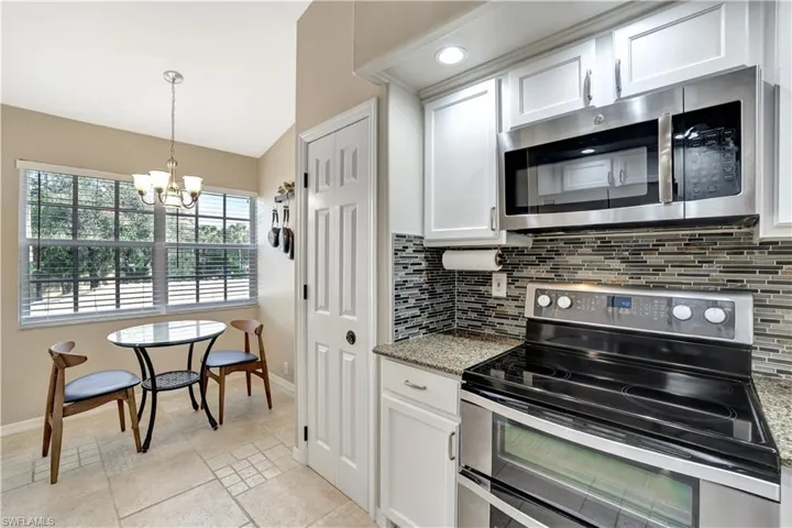 Kitchen featuring appliances with stainless steel finishes, decorative backsplash, white cabinets, and vaulted ceiling