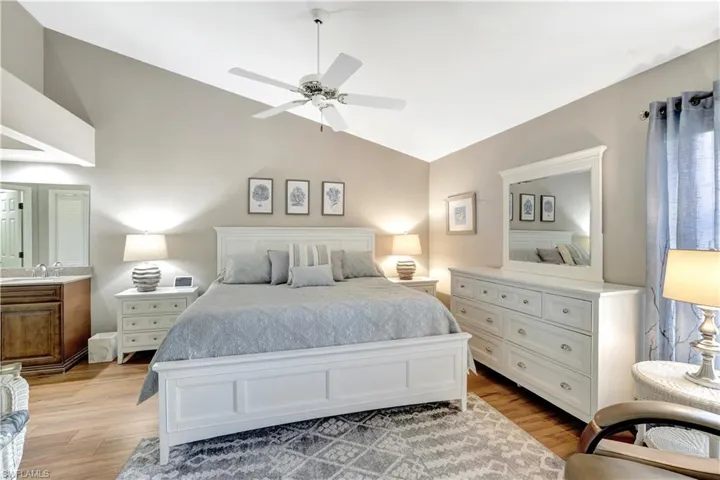 Bedroom featuring light wood-type flooring, vaulted ceiling, and a ceiling fan
