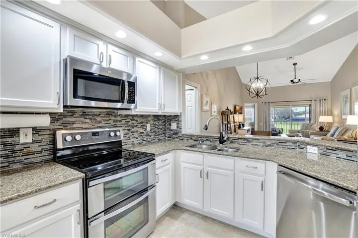 Kitchen featuring appliances with stainless steel finishes, decorative backsplash, recessed lighting, ceiling fan, and white cabinets