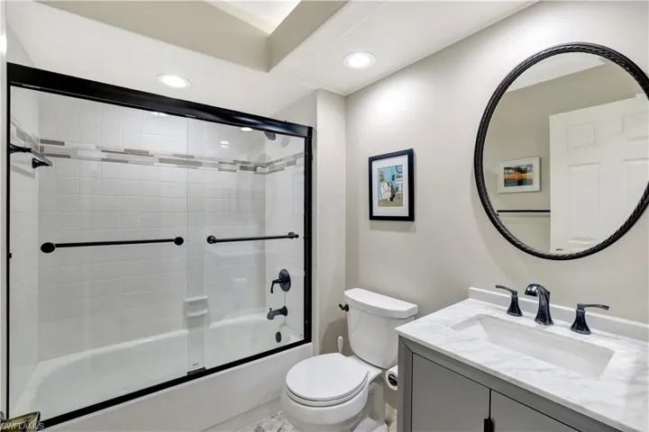 Bathroom featuring vanity, shower / bath combination with glass door, and recessed lighting