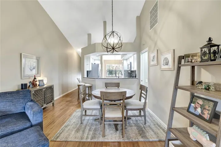 Dining area with a chandelier, high vaulted ceiling, and wood finished floors