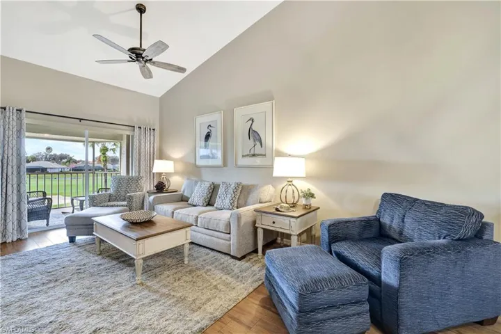 Living room with a ceiling fan, wood finished floors, and high vaulted ceiling