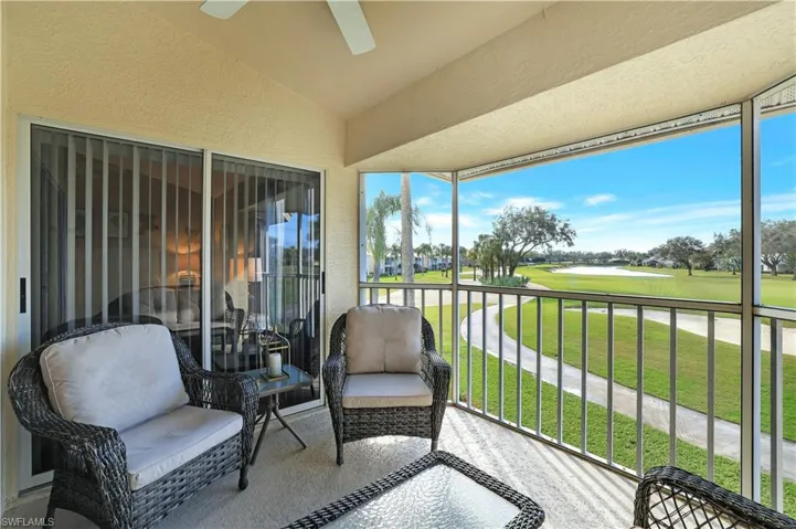 Balcony featuring view of golf course, ceiling fan, and a water view