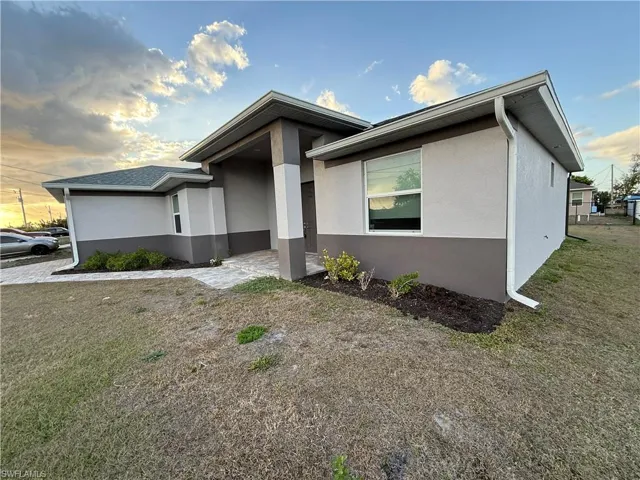 View of front facade featuring stucco siding and a yard