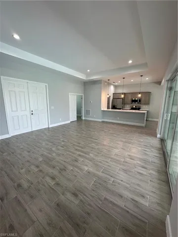 Unfurnished living room featuring wood tiled floors, recessed lighting, and a tray ceiling