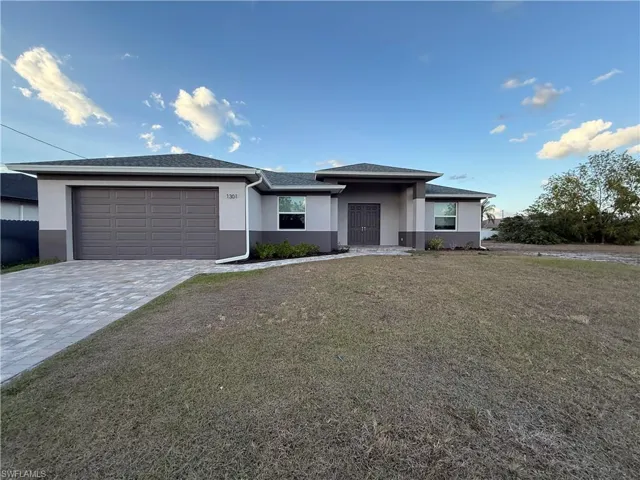 View of front of property with stucco siding, decorative driveway, a garage, and a front lawn