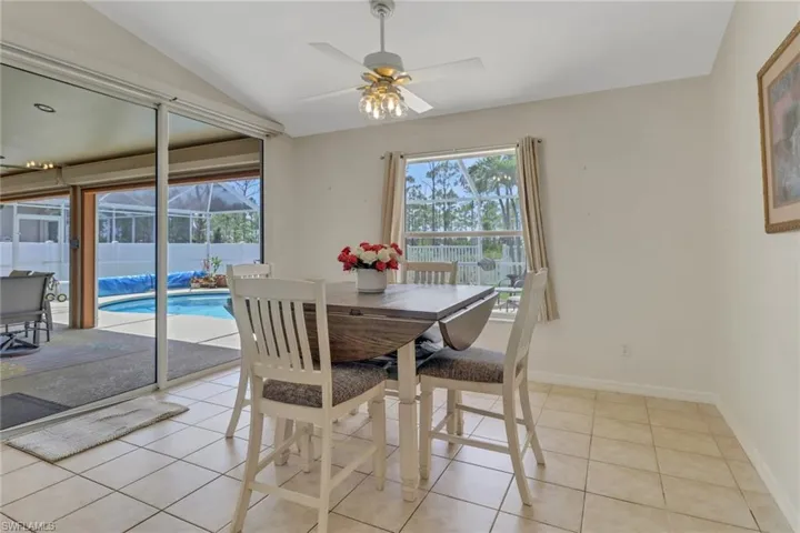 Dining area with sliding doors, a ceiling fan, baseboards, light tile patterned floors, and lofted ceiling