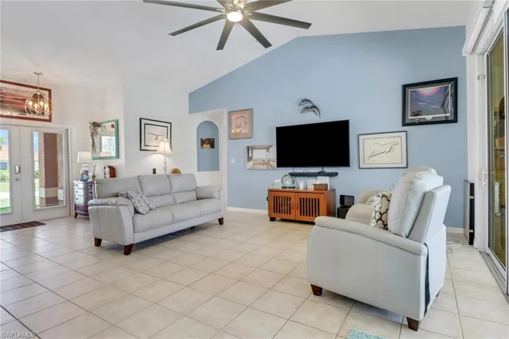 Living room featuring a chandelier, a ceiling fan, light tile patterned floors, french doors, sliding doors, and baseboards