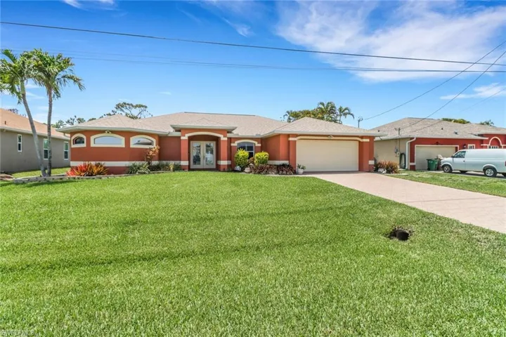 Beautiful home with french doors, a garage, driveway with pavers, stucco siding, and a front lawn