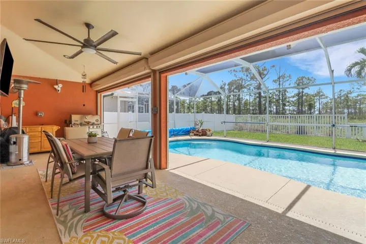View of swimming pool, featuring motorized roll down shutters, a ceiling fan, a fenced backyard, a patio, lanai, and outdoor dining and entertainment space