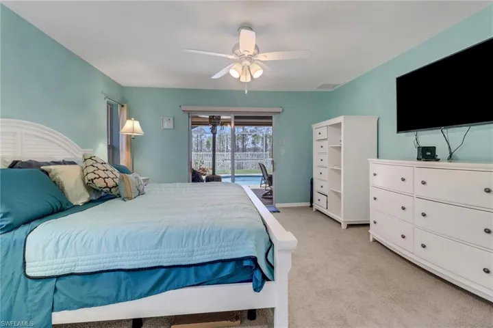Bedroom with brand new light carpet, access to pool outside, ceiling fan, and baseboards