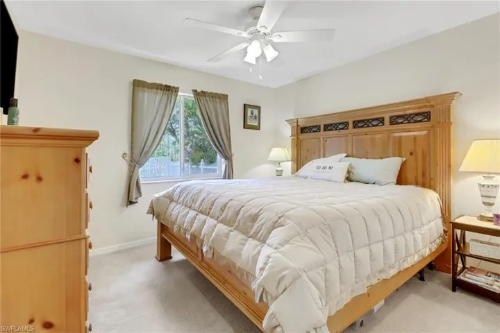 Bedroom with light colored carpet, a ceiling fan, and baseboards