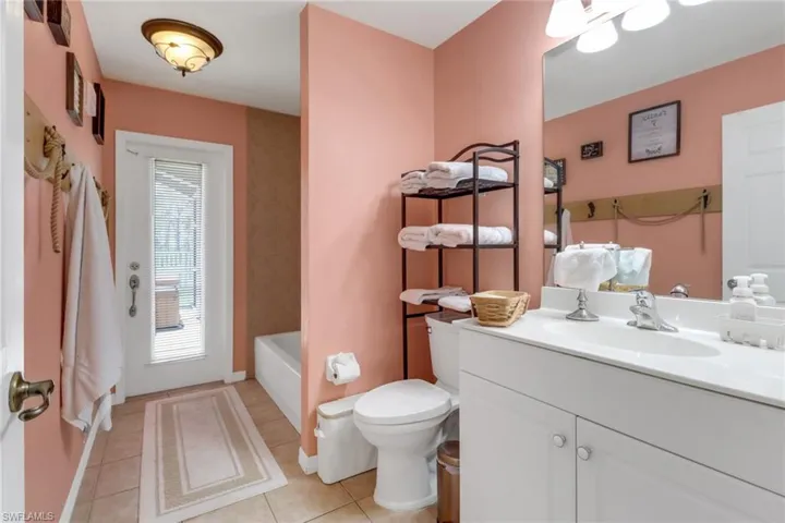 Bathroom with access to the pool, lanai, and hot tub, with vanity, toilet, a bathtub, shower, and tile patterned floors