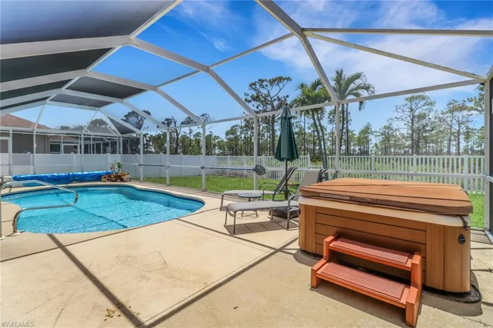 View of pool featuring a hot tub, a fenced backyard, a patio, and lanai