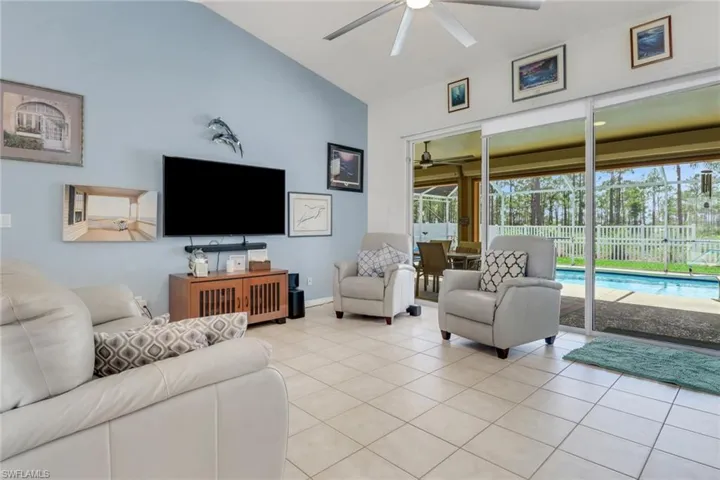 Living area featuring a ceiling fan, light tile patterned floors, sliding doors, and high vaulted ceiling