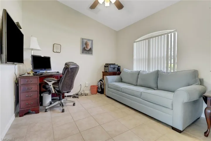 Den/office featuring a ceiling fan, lofted ceiling, light tile patterned floors, and baseboards