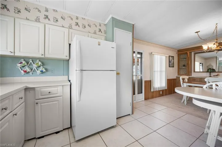 Kitchen area featuring white cabinetry, a white refrigerator, and white tiled flooring