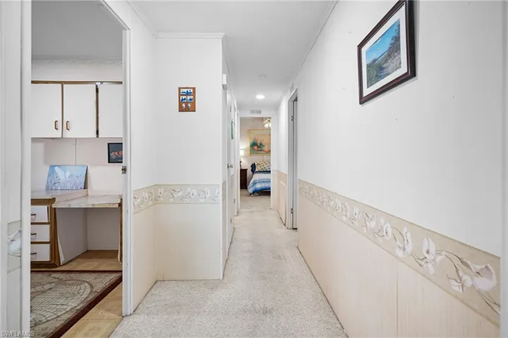 Hallway featuring light-toned carpeting and decorative wainscoting