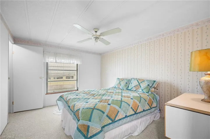Bedroom featuring light-colored carpet flooring, a window with horizontal blinds, and a ceiling fan