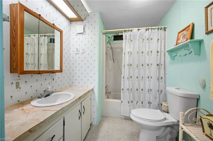 Bathroom featuring a full vanity with an integrated sink, a medicine cabinet with mirrored doors, and a full bathtub with a shower