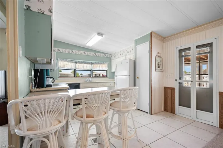 Kitchen featuring tiled flooring, white appliances, light-colored countertops, and multiple windows
