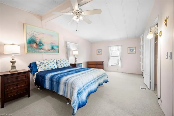 Spacious bedroom featuring light-colored carpeting, a ceiling fan, and painted paneling on the ceiling