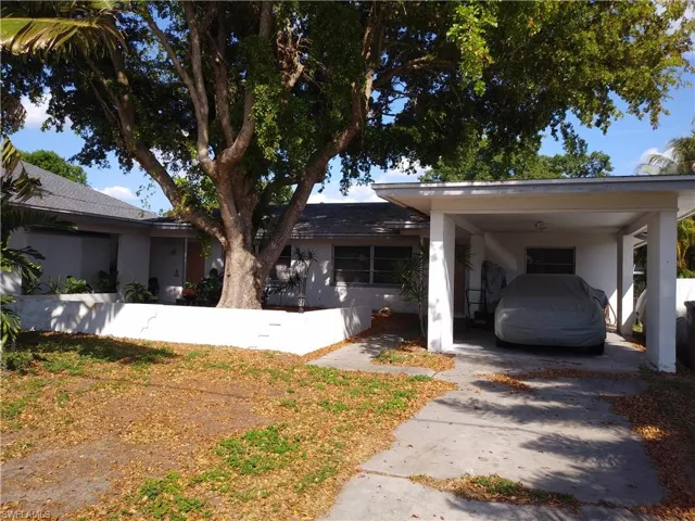 Ranch-style house featuring a carport, driveway, stucco siding, and a fenced front yard