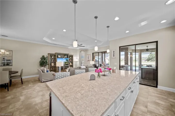 Kitchen with white cabinets, ceiling fan, open floor plan, a kitchen island, and pendant lighting