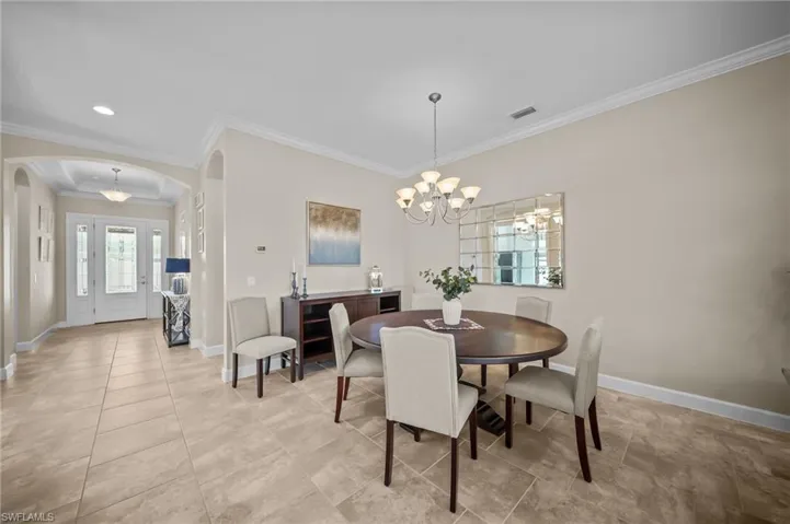 Dining room featuring arched walkways, suspended lighting, and ornamental molding