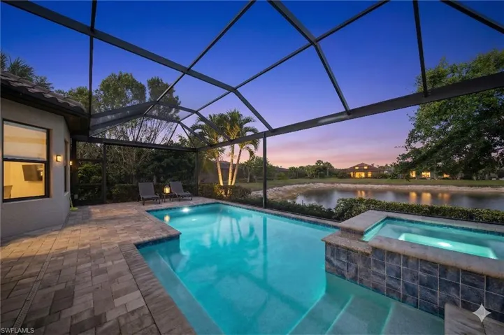 Combined pool / hot tub featuring a sunroom, glass enclosure, a patio area, and a water view