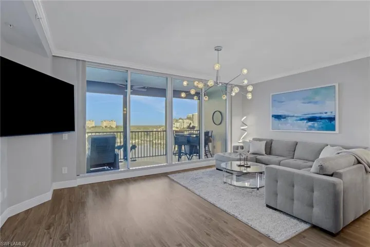 Living area featuring crown molding, wood finished floors, hanging lights, and floor to ceiling windows