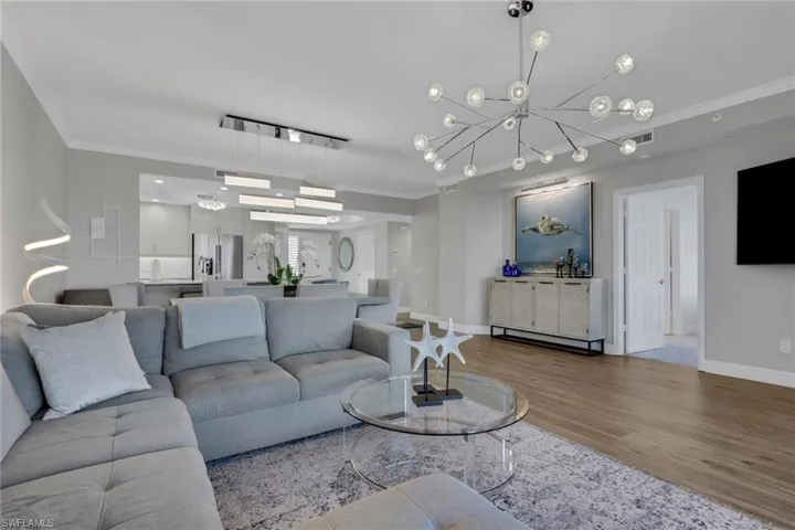 Living room with ornamental molding, wood finished floors, and hanging lights