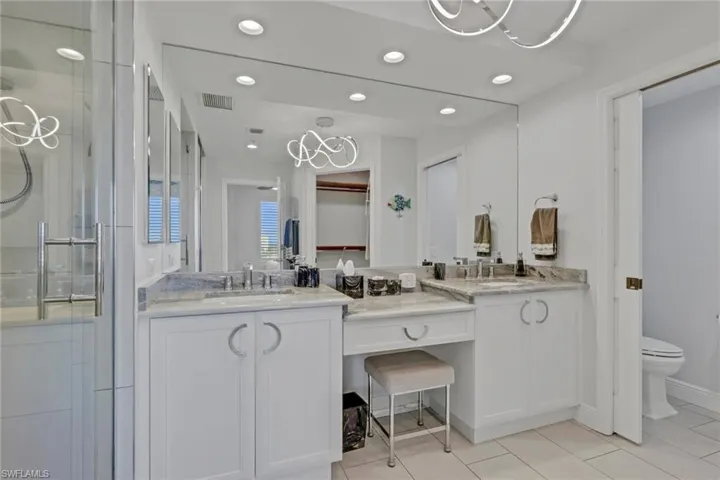 Bathroom with a stall shower, double vanity, a chandelier, and light tile patterned floors