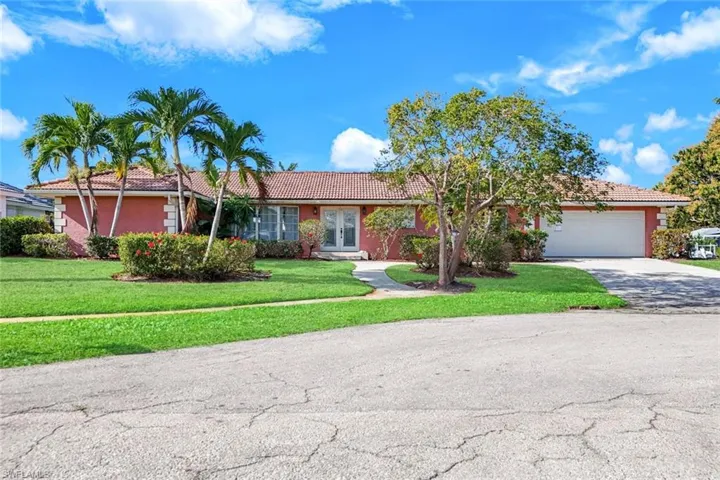 Ranch-style home with a tiled roof, an attached garage, driveway, a front yard, and french doors