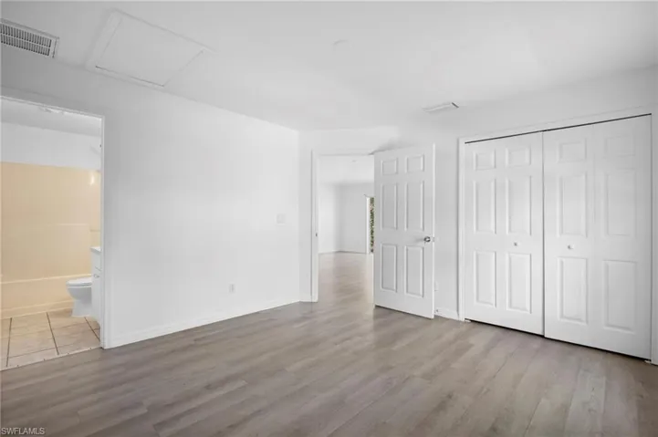 Unfurnished bedroom with light wood finished floors, attic access, a closet, and ensuite bathroom