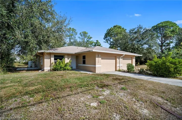 Single story home featuring stucco siding, driveway, an attached garage, and a front lawn