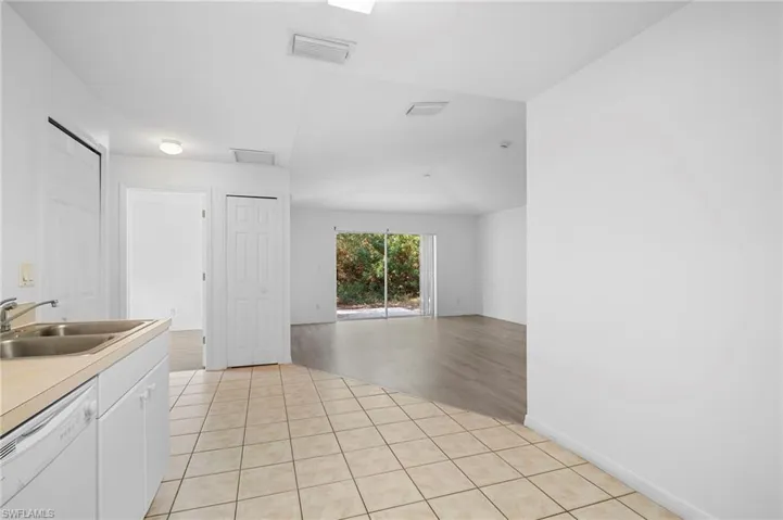 Kitchen with dishwasher, light countertops, white cabinetry, and light tile patterned floors